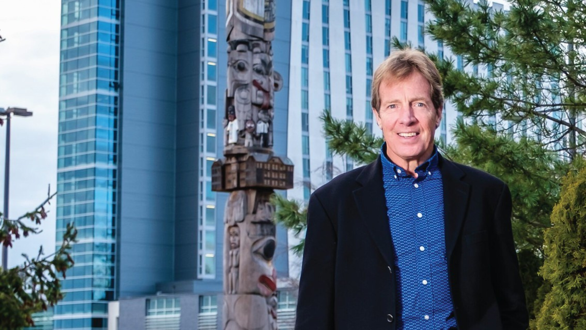 Reid Carter stands in front of building and totem pole.