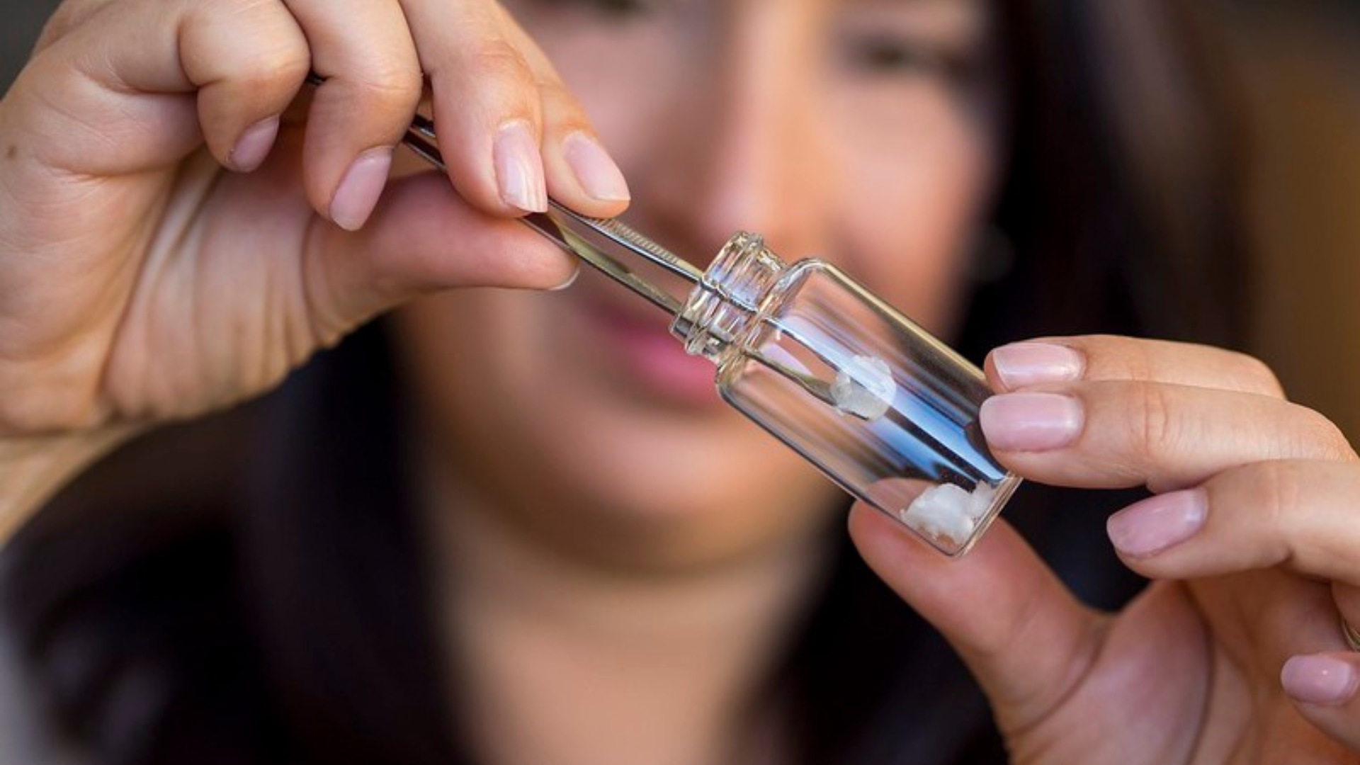 Emily Cranston uses tweezers to grab a piece of flexible nanocellulose aerogel.